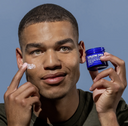 Blu Atlas green eyed dark skin male model applying exfoliating face scrub