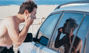 A surfer is applying sunscreen looking in his car window