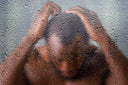 A man in the shower applying conditioner to his hair.