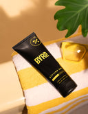 A bottle of styling gel on a yellow and white striped towel with a leaf accent.