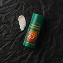 A flat lay of Brooklyn Grooming's Pilgrim's Deodorant with a smudge of DEO to it's left.
