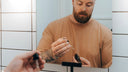 Man in a brown shirt squeezing some serum into a doppler.