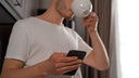A guy reading his phone while drinking coffee.