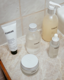 Five Comune products on a bathroom sink.