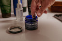 A guy dipping his fingers into a face mask tub.