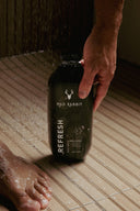 A man picking up a bottle of Mad Rabbit in the shower.