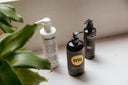 Three different conditioner bottles next to a plant.