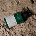 Green bottle with pump on a sandy surface