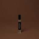 Small clear bottle with black cap on a brown background