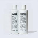 Two bottles of shampoo and conditioner on a light gray background