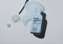 Blue atlas serum bottle with dropper on a light gray background