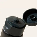Black bottle of Cardon SPF + Moisturizer with open lid on a light beige background