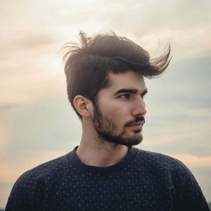Man with wavy hair on a cloudy day.