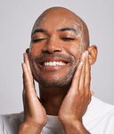 Man applying cream to his face with a neutral background