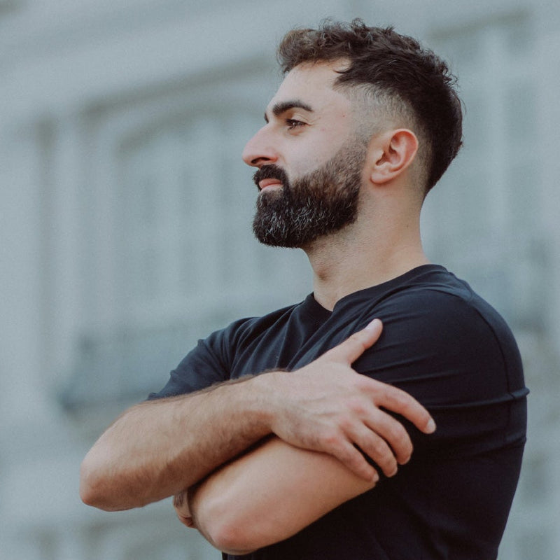 Man with a beard against a city backdrop.