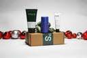 Three products on top of a christmas box with christmas balls behind.