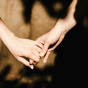 Two people holding hands with a blurred background
