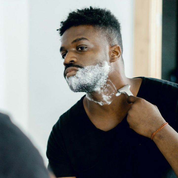 Man shaving with foam in front of a mirror